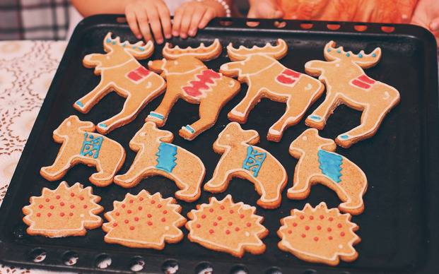 Kinder backen Weihnachtsplätzchen auf einem Blech.