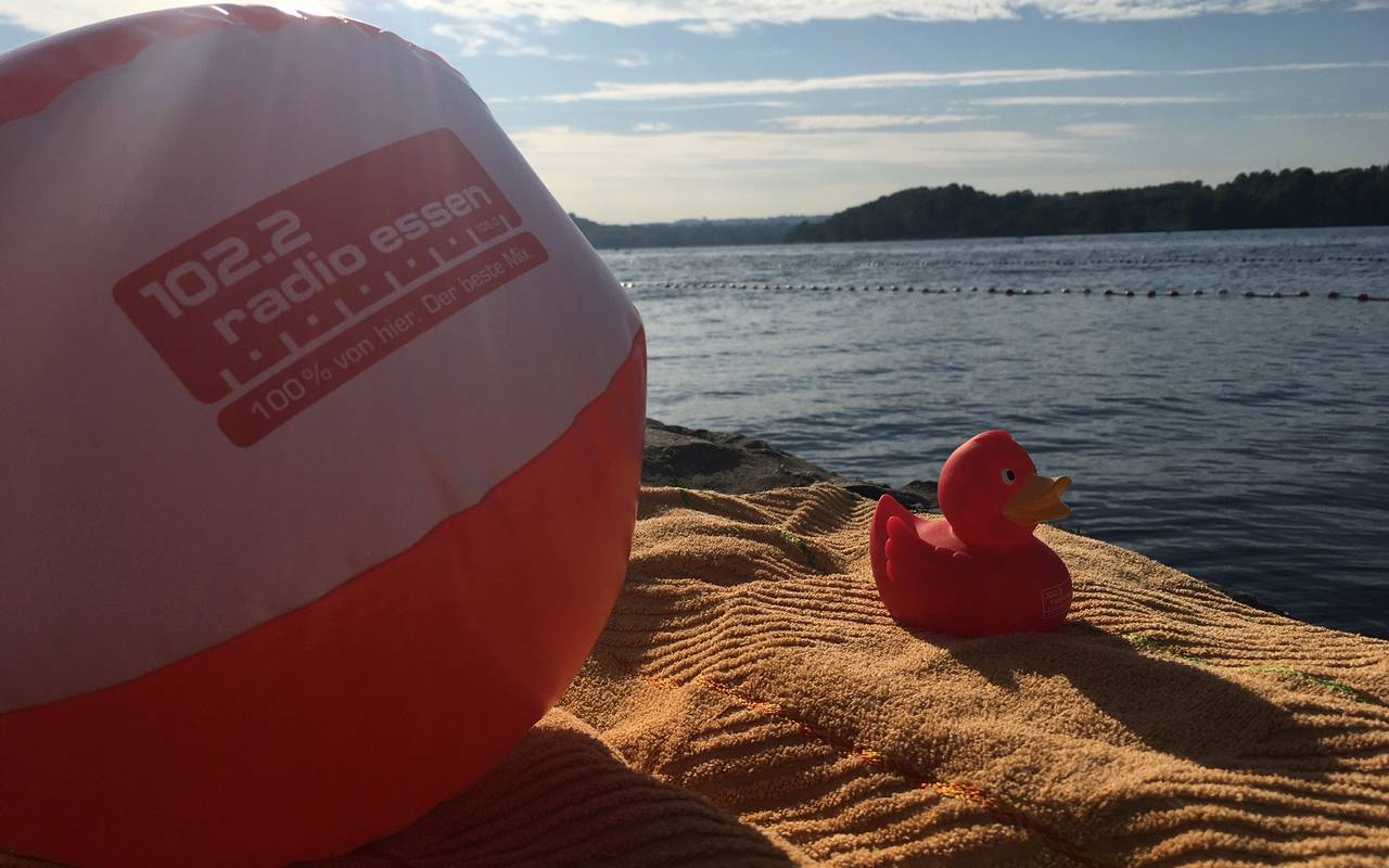 Radio Essen-Badeente Erna mit rot-weißem Radio Essen-Wasserball im Sand am Baldeneysee