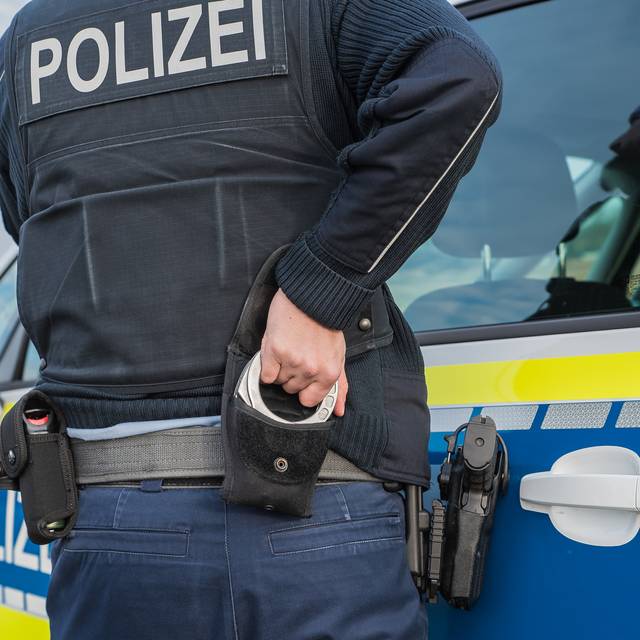 Ein Polizist nutzt Handschellen zur Festnahme (Symbolbild).