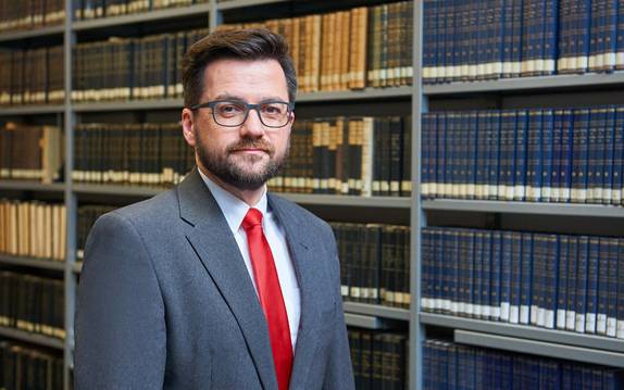 Chef der Essener SPD und Landtagsabgeordneter Thomas Kutschaty im Anzug vor einer Bücherwand