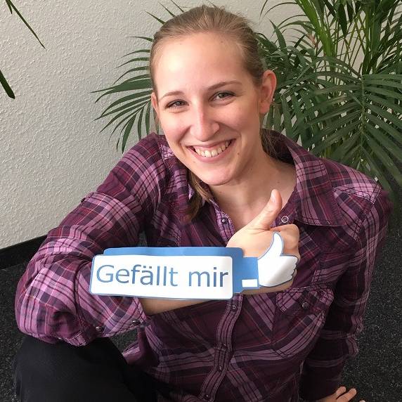 Radio Essen-Moderatorin Larissa Schmitz mit einem Gefällt-mir-Daumen von Facebook vor Blumen.