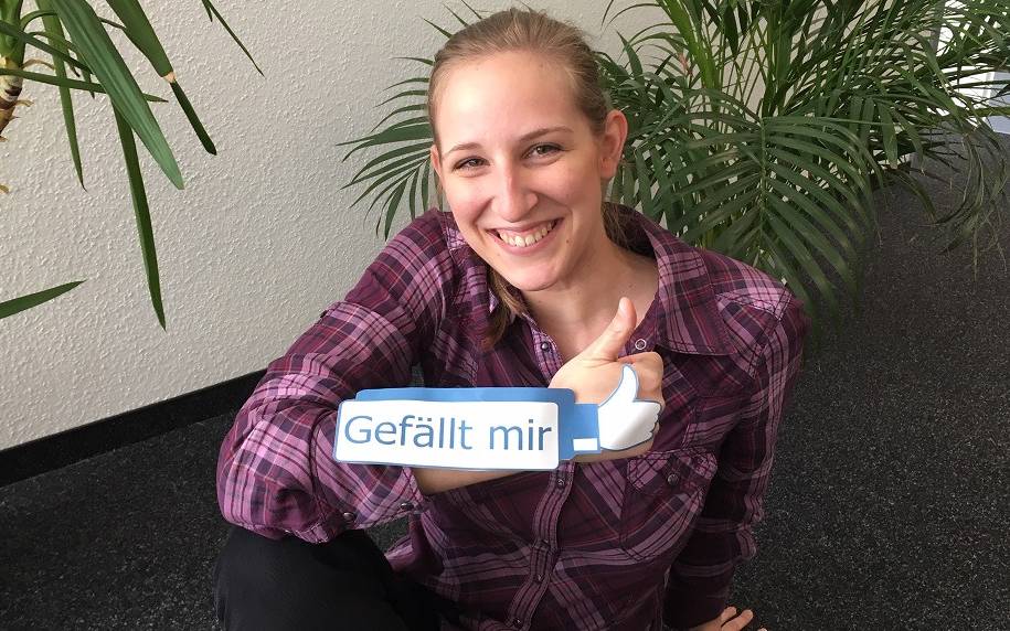 Radio Essen-Moderatorin Larissa Schmitz mit einem Gefällt-mir-Daumen von Facebook vor Blumen.