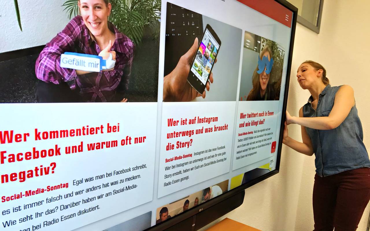 Radio Essen-Moderatorin Larissa Schmitz guckt hinter einen Bildschirm, auf dem die neue Website von Radio Essen zu sehen ist.