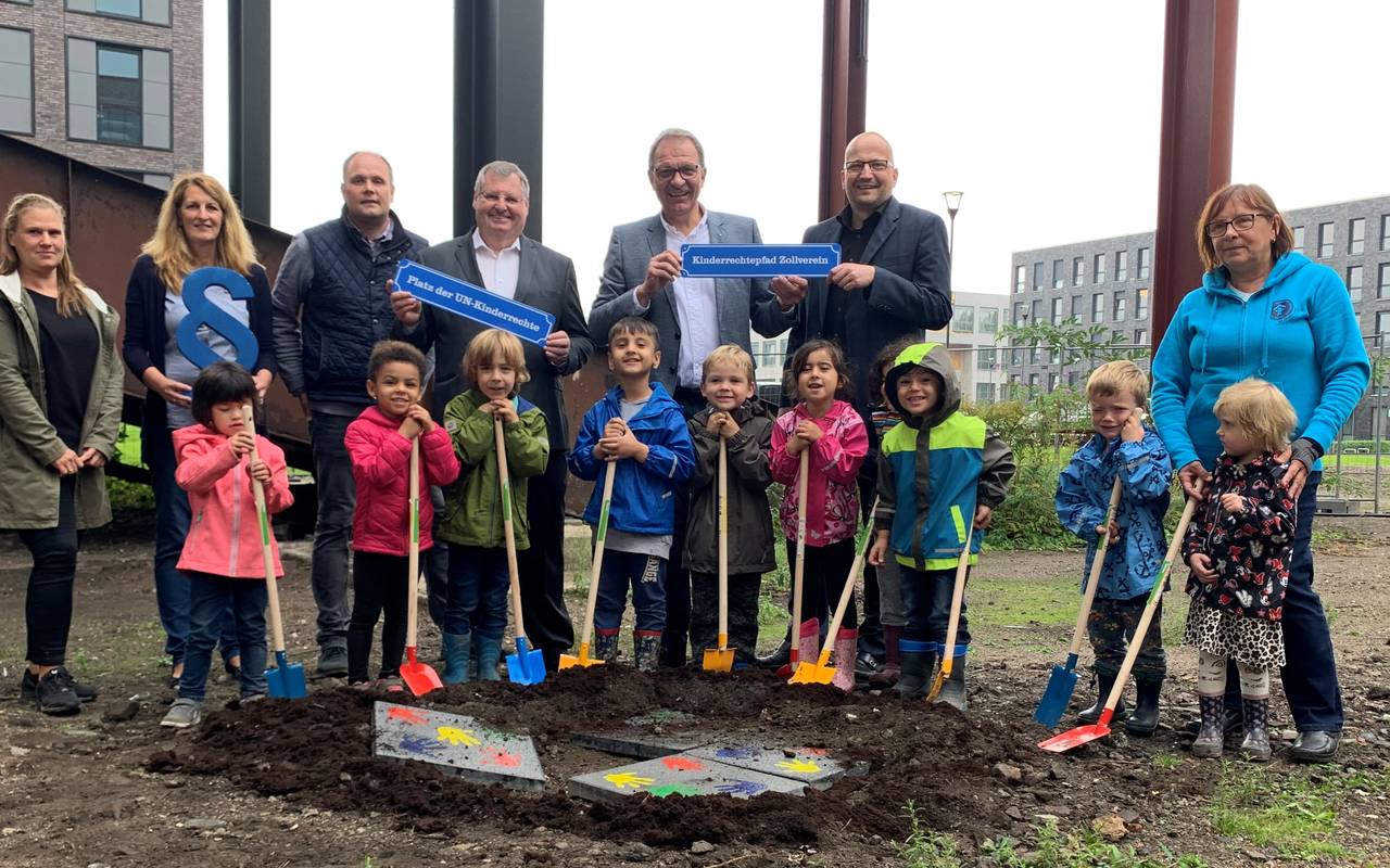Erwachsene und Kinder legen die Grundsteine für den UN Kinderrechtepfad. Die Steine sind bunt bemalt, unter anderem mit den handabdrücken der Kinder.