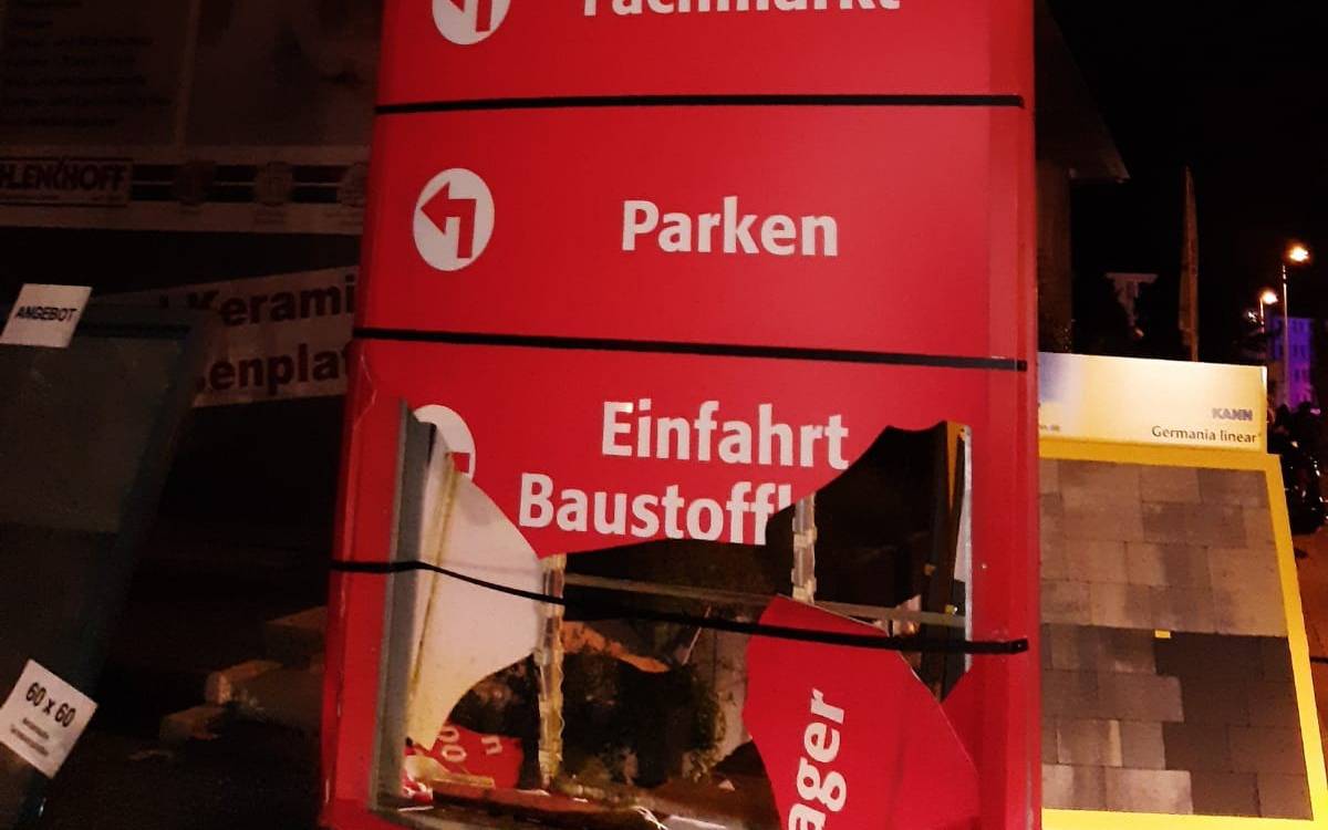 Das Bild zeigt die Werbetafel eines Baustoffhandels. Es hat ein großes Loch in der Mitte.