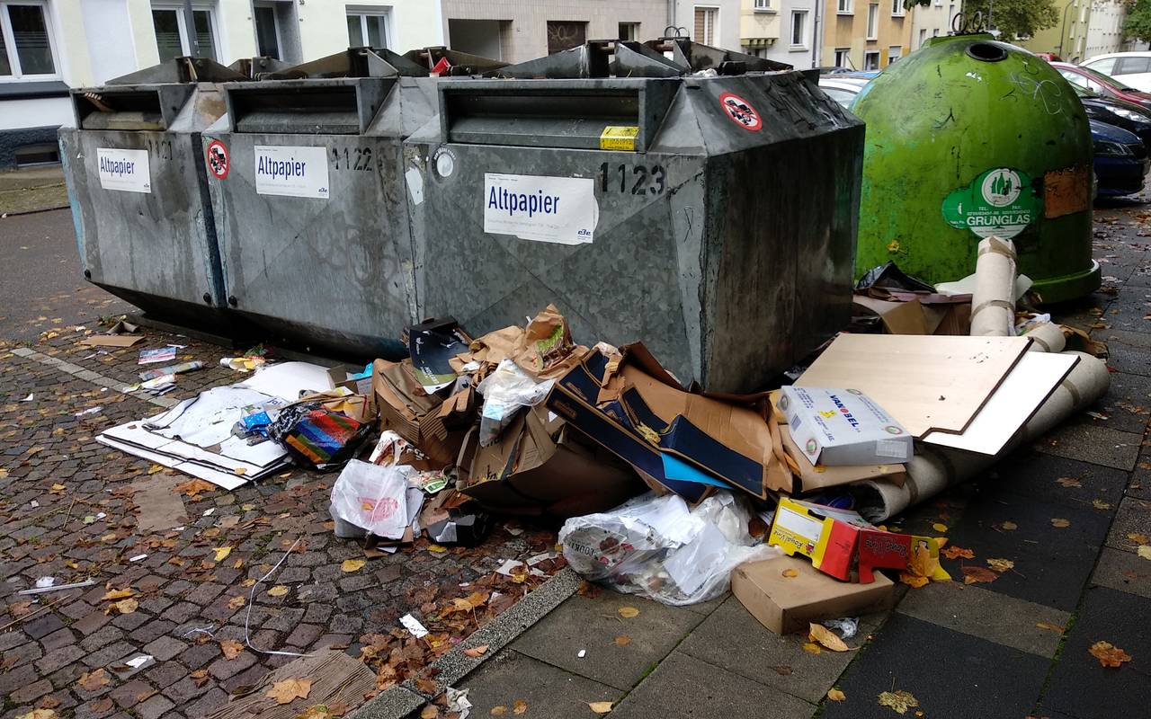 Container, daneben liegt viel Müll auf dem Boden: Kartons, Pappe und auch alte Teppiche.