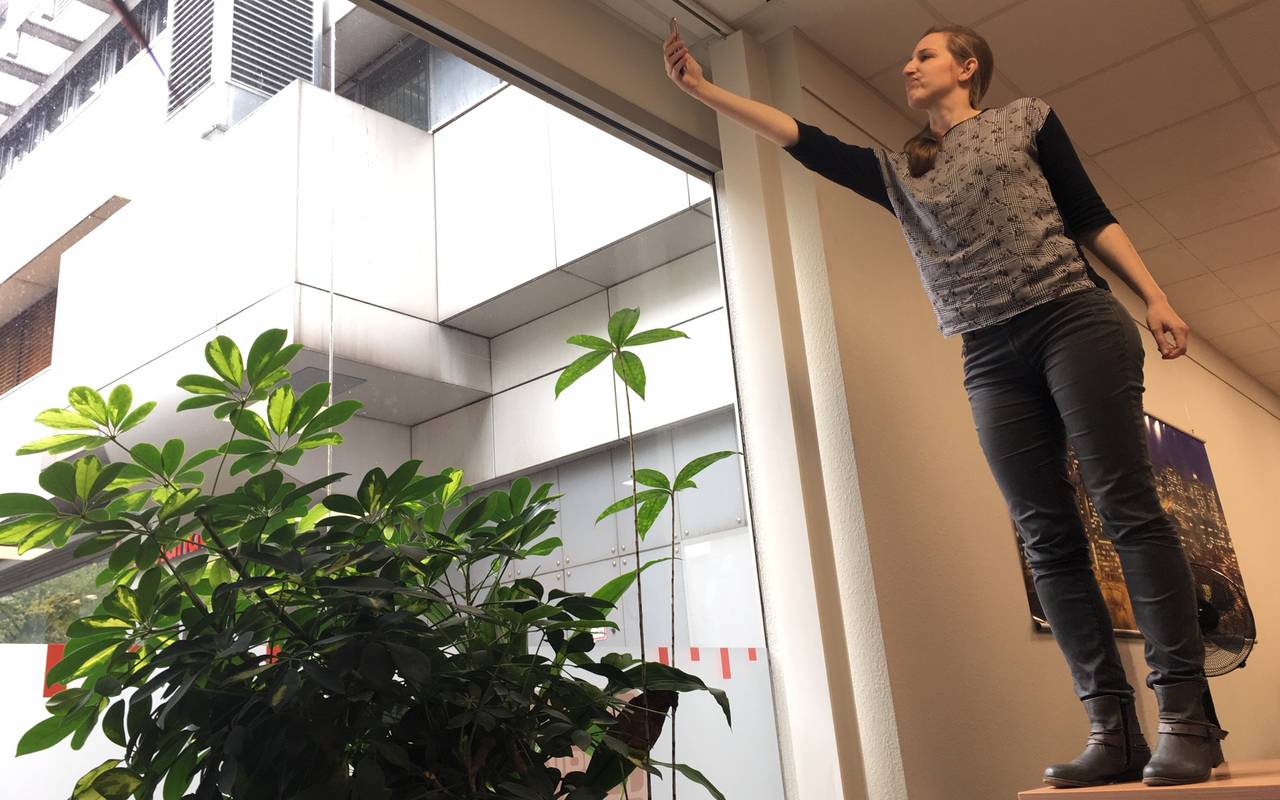 Larissa Schmitz von Radio Essen sucht mit ihrem Handy auf dem Schreibtisch am Fenster nach gutem Empfang.