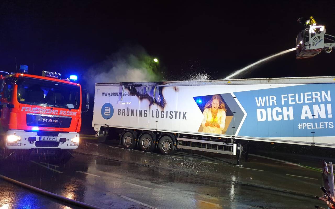 Das Bild zeigt den qualmenden LKW-Anhänger. Die Feuerwehr löscht mit einem dicken Schlauch.