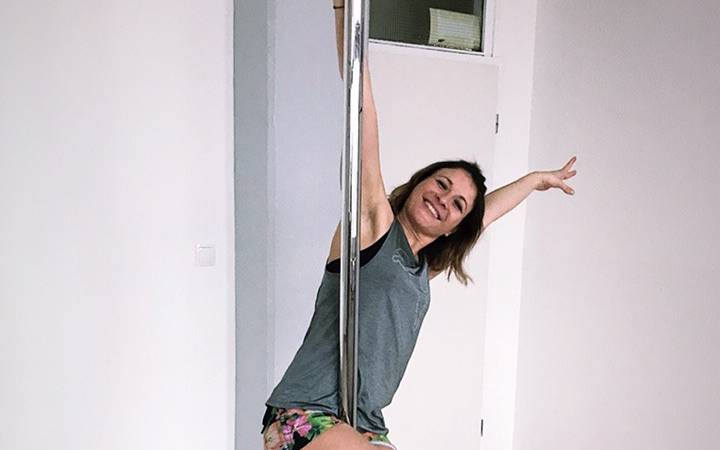 Frau hängt an der Stange und lächelt in die Kamera