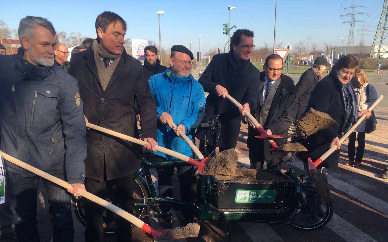 Personen schaufeln Erde mit Spaten aus einem Lastenrad.