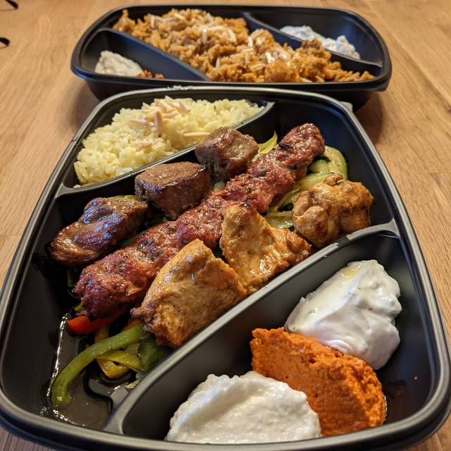 Drei Sorten gegrilltes Fleisch auf Gemüsebett, dazu Reis und Dips (Maschwiyat)