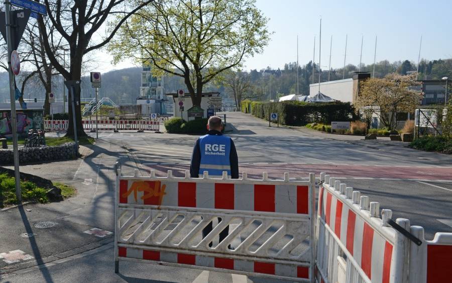 Ein Mitarbeiter der RGE Servicegesellschaft Essen mbH steht am abgesperrten Einmündungsbereich an der Freiherr-vom-Stein-Straße zum Parkplatz am Regattaturm.