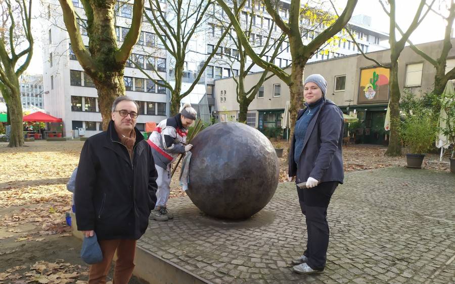 Das Kunstwerk "Ein leichtes Spiel" mit seinen Stahl-Elementen am Salzmarkt wird gereinigt. Kulturdezernent Muchtar Al Ghusain (links), und Mitarbeiterinnen der Restaurationsfirma "Zur Schmiede" Clara Buchegger (Mitte) und Anna Windmüller (rechts).