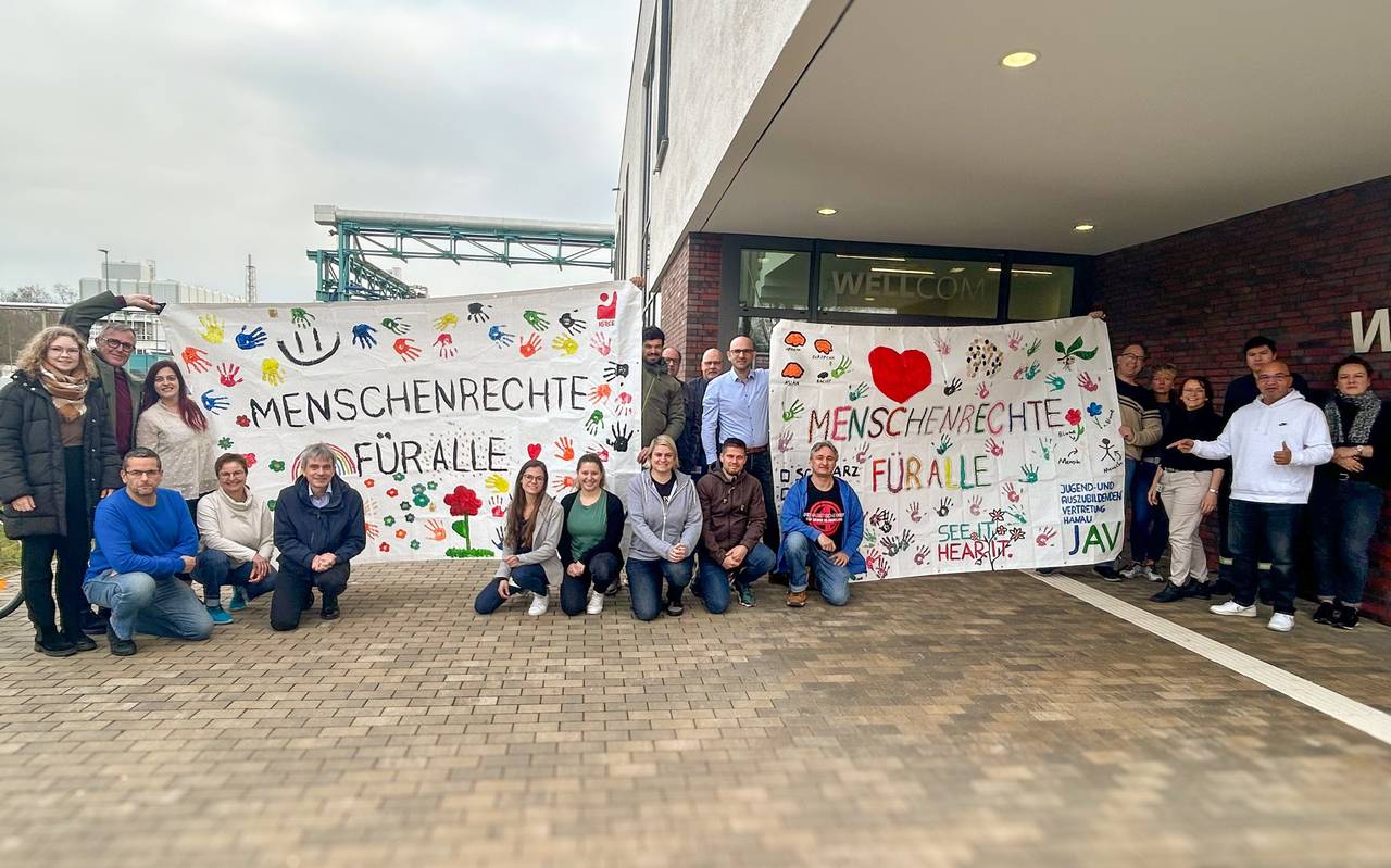 Auszubildende und Arbeitnehmervertreter von Evonik halten Plakate mit der Aufschrift "Menschenrechte für alle".