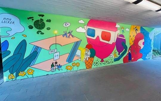 Die beiden Tunnelwände des U-Bahn-Ausgangs in Richtung Rhein-Ruhr-Zentrum in Mülheim erstrahlen in neuem Glanz – gestaltet in enger Zusammenarbeit mit dem Institut für Ausbildung in Bildender Kunst und Kunsttherapie (IBKK) Bochum.