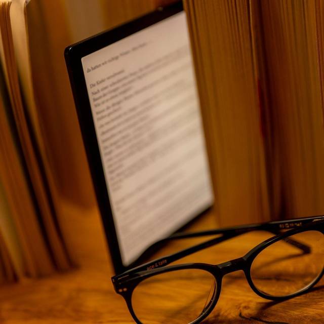 E-Book-Reader steht zwischen Büchern auf einem Tisch