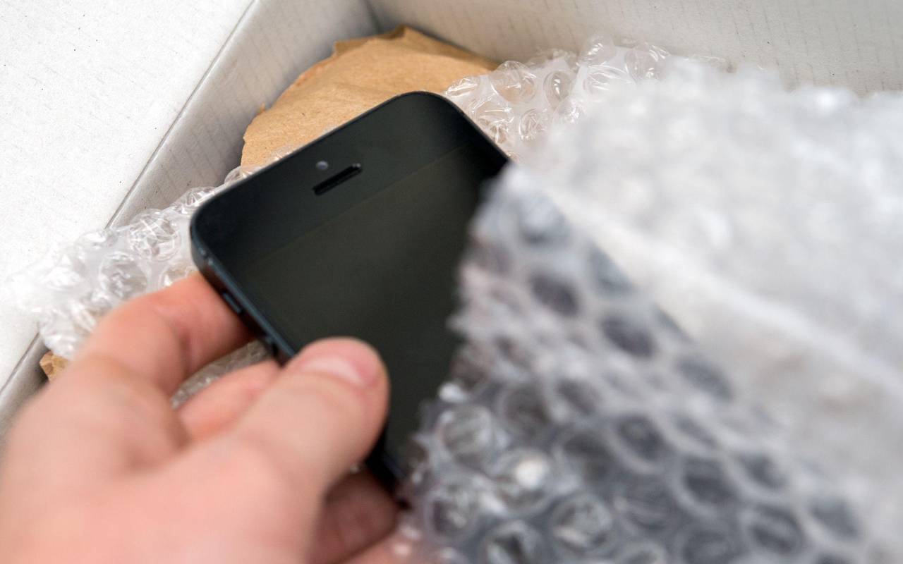 Person nimmt ein Smartphone aus einem Päckchen