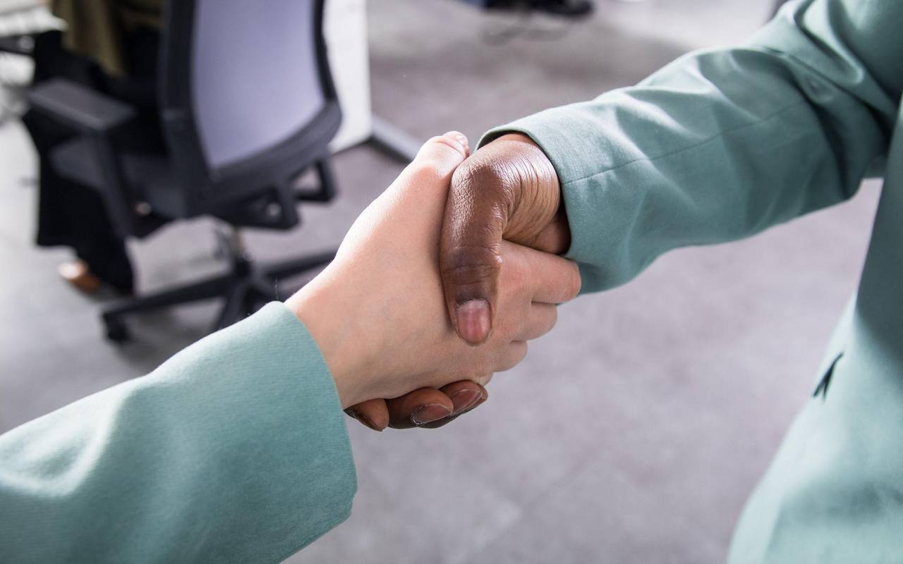 Zwei Personen reichen sich in einem Büro die Hand