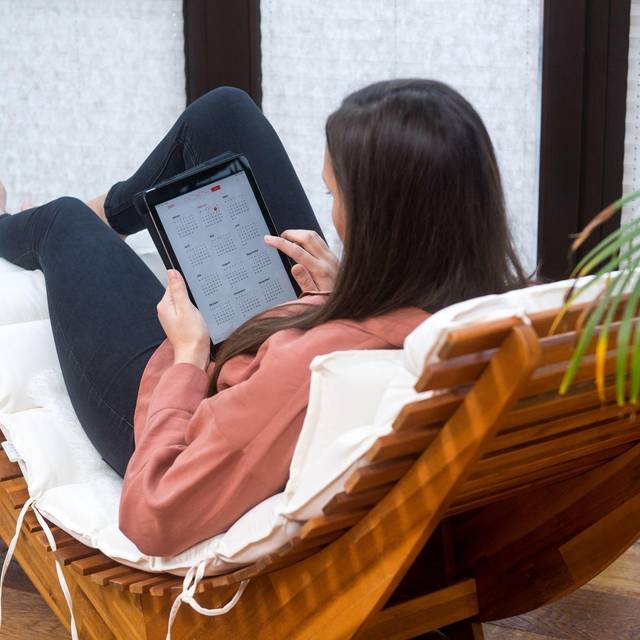 Eine Frau guckt auf einem Tablet auf einen Kalender