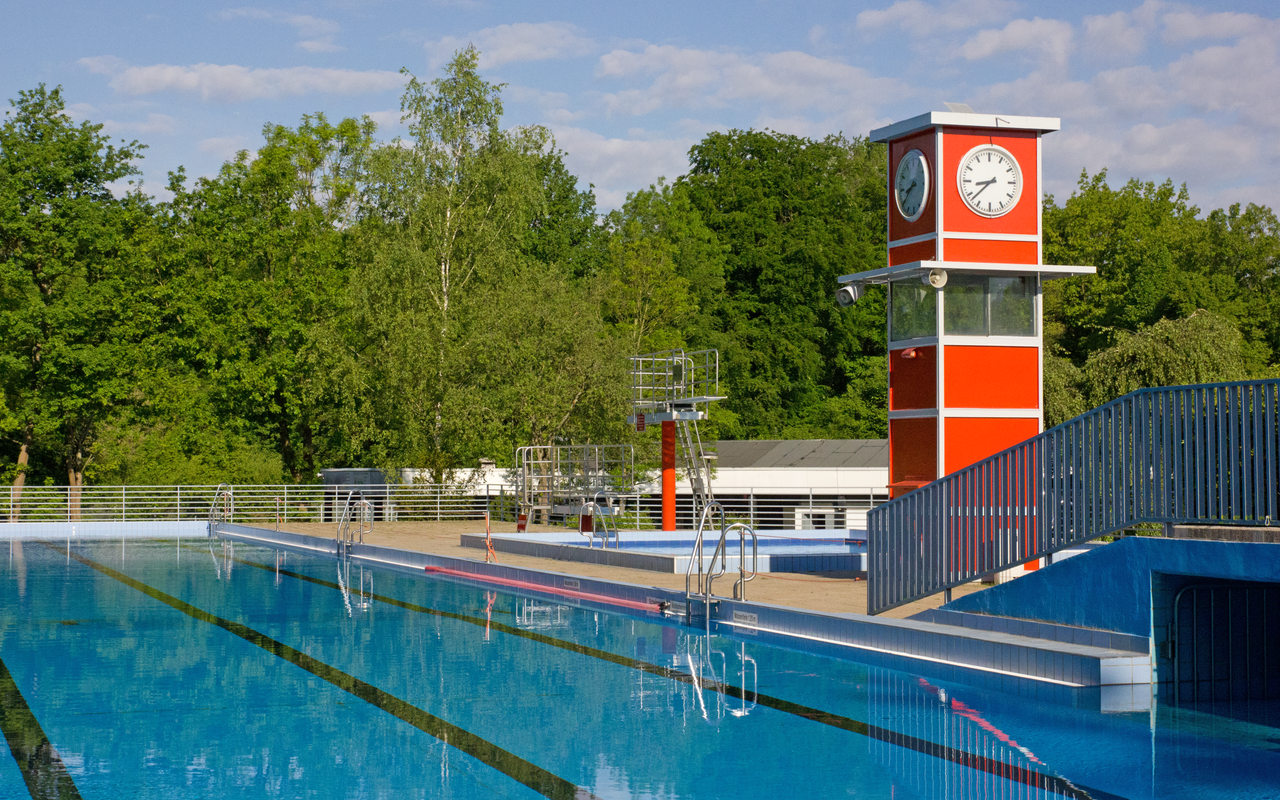 Das Sportbecken im Freibad Oststadtbad in Essen Freisenbruch mit dem typischen roten rechteckigen Turm mit Uhr.