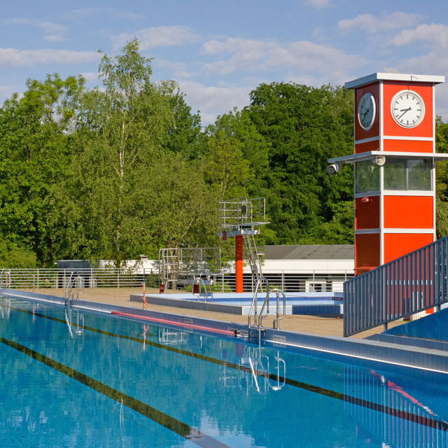 Das Sportbecken im Freibad Oststadtbad in Essen Freisenbruch mit dem typischen roten rechteckigen Turm mit Uhr.