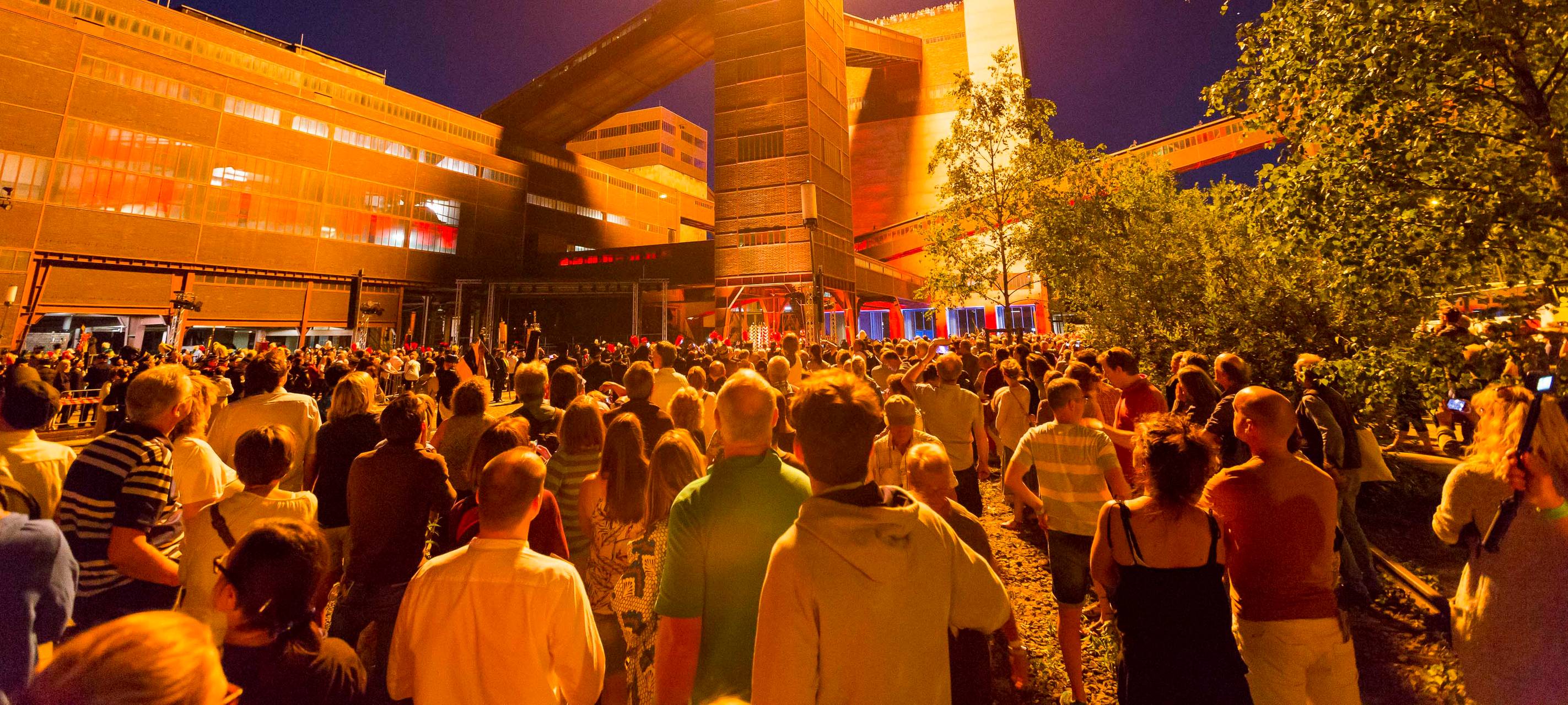 Viele Besucher schauen einer Feuershow bei der Extraschicht auf Zollverein in Essen zu.
