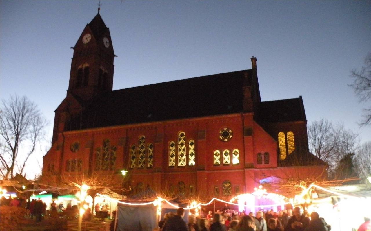 Ein großer rot-brauner Dom mit spitzem Turm und Menschen bei einem Gemeindefest davor.