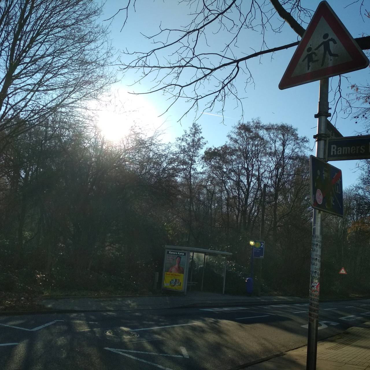 Eine Bushaltestelle in Essen "Ramers Kamp" mit einer Straße davor und einem Achtung Kinder-Schild.
