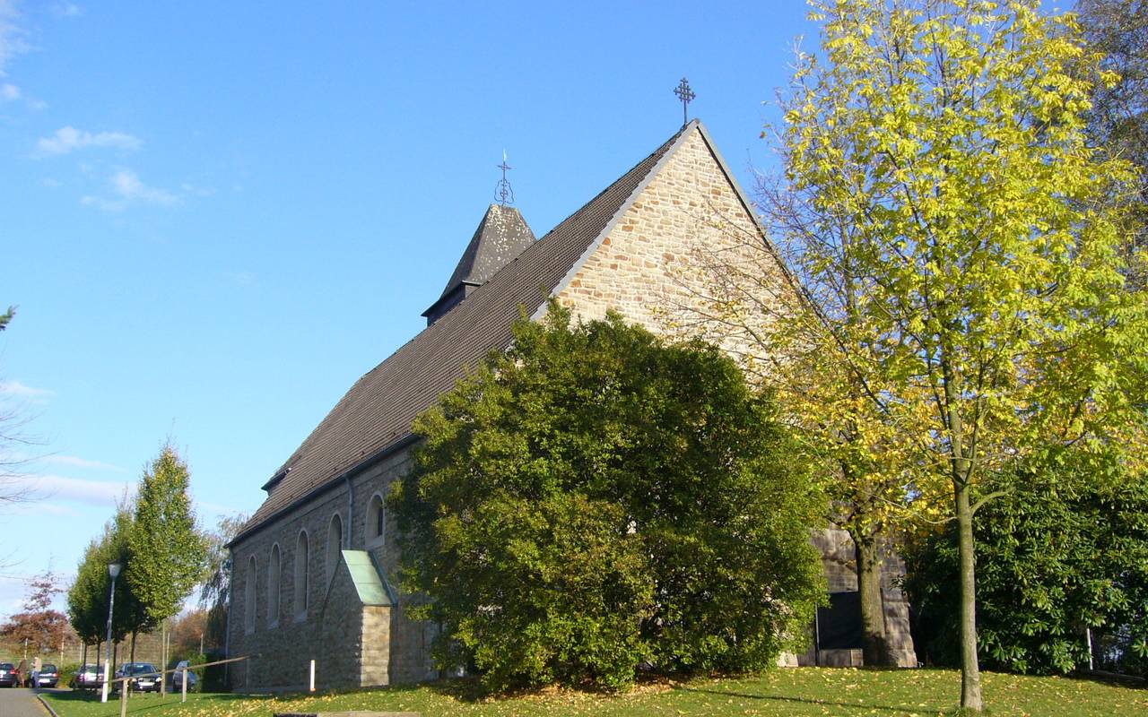 Kleine grau-braune Dorfkirche mit einem kleinen Turm direkt an einer Straße.