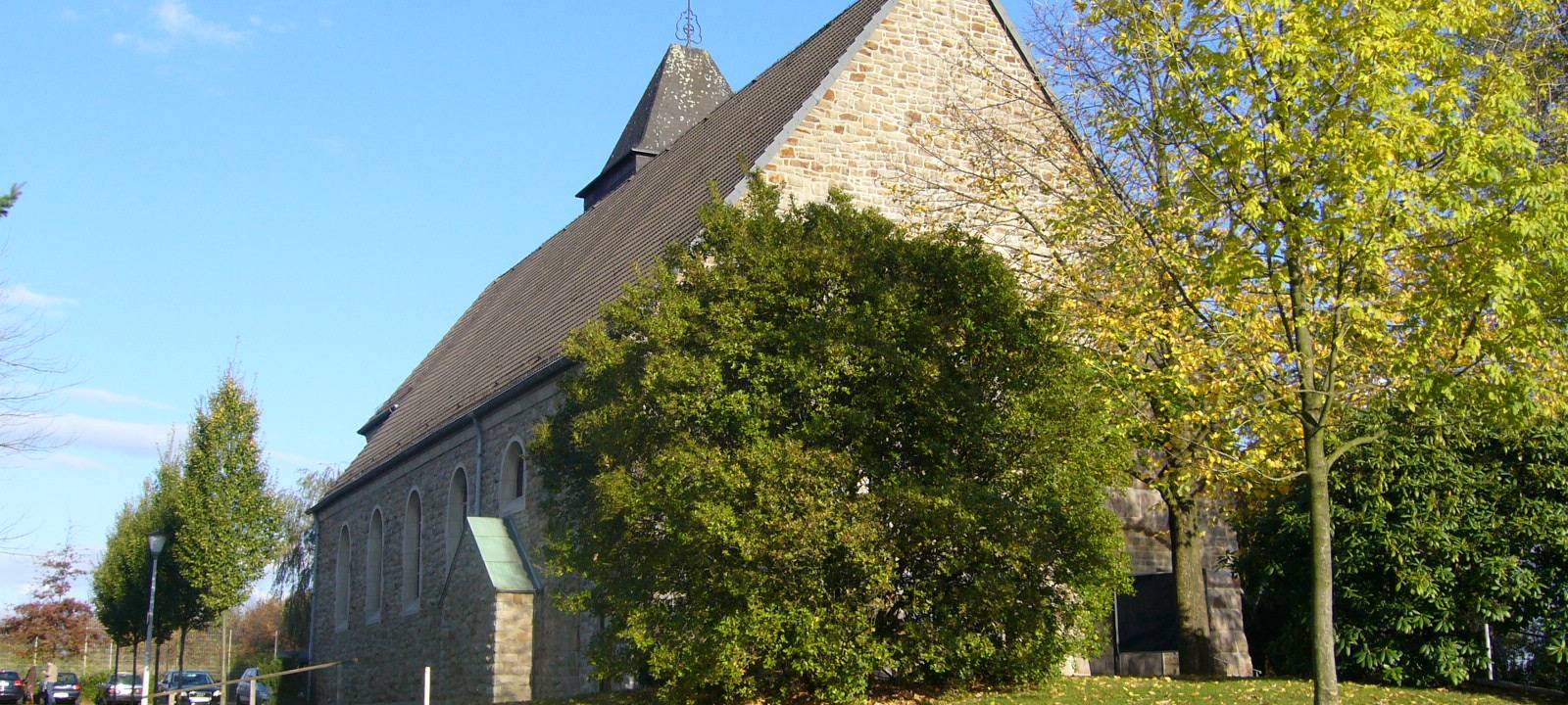 Kleine grau-braune Dorfkirche mit einem kleinen Turm direkt an einer Straße.