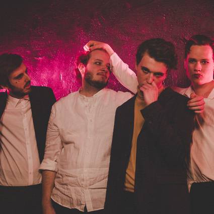 Vier Jungs der Band DOTE aus Essen vor einem violetten Hintergrund.