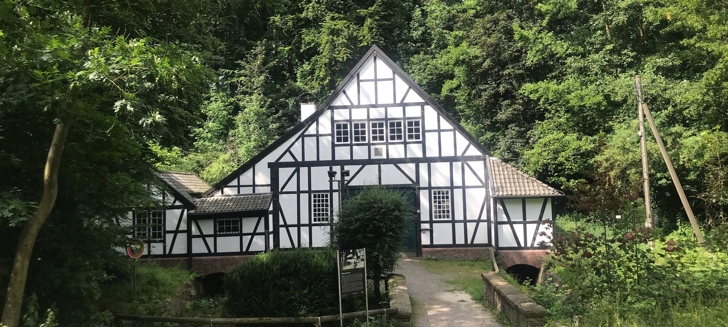 Das weiße Fachwerkhaus des Halbachhammers im Essener Stadtteil Fulerum, umgeben von Bäumen.