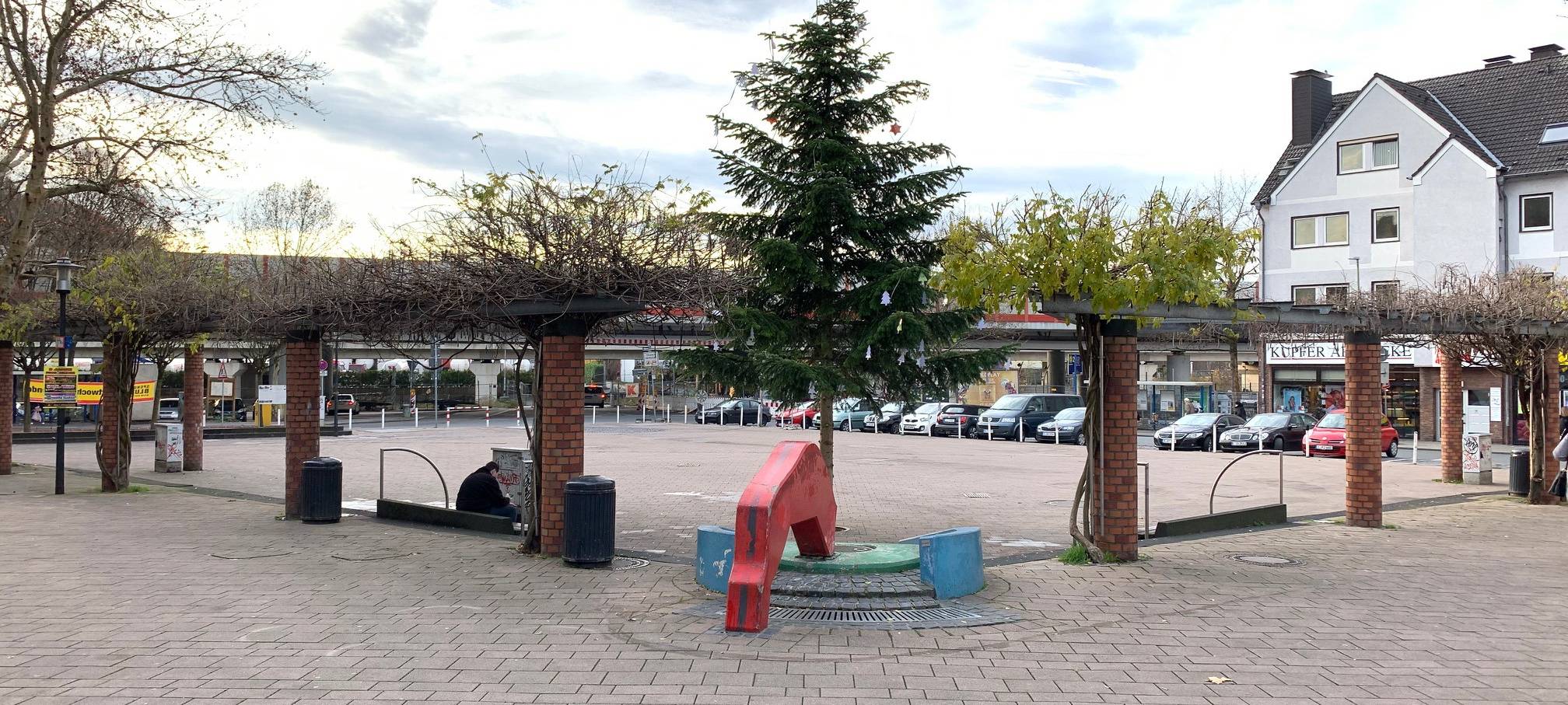 Ein Viereckiger Marktplatz vor einer Autobahnbrücke am Kupferdreher Bahnhof.