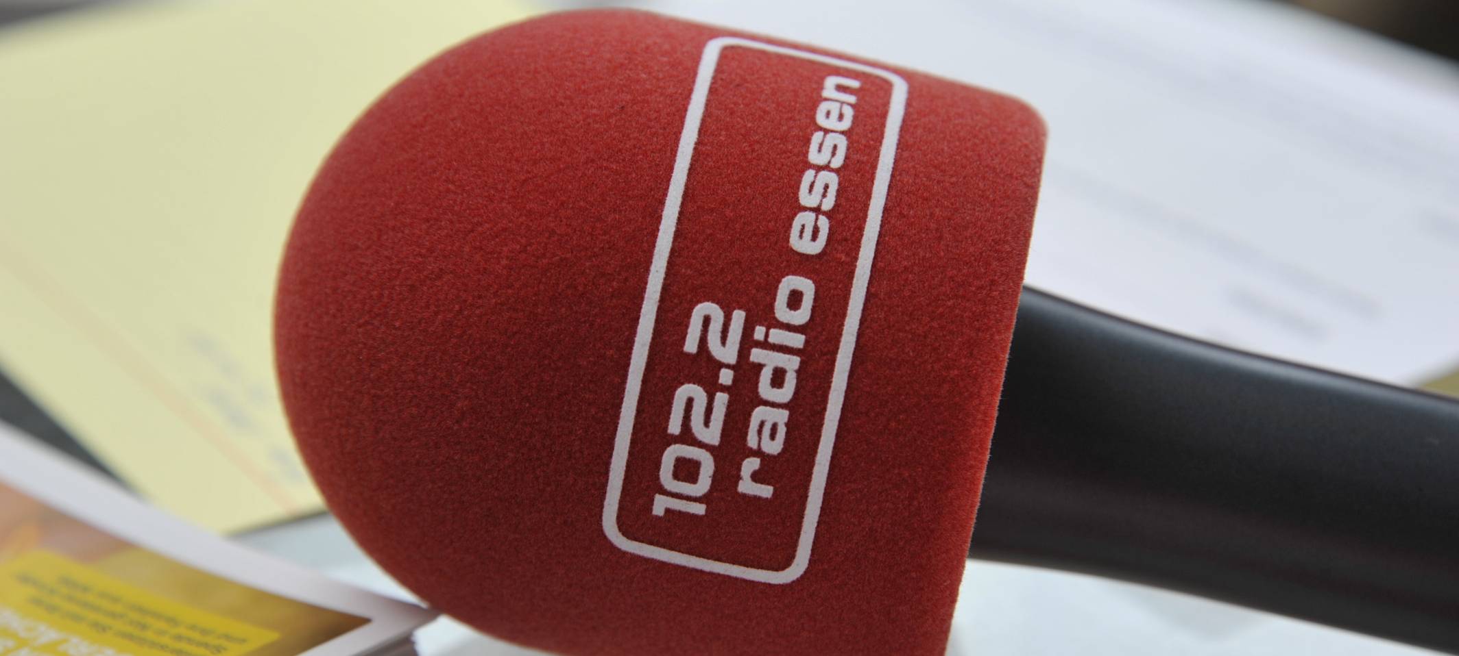 Das Mikro an schwarzem Stil mit rotem Schaumstoff-Ploppschutz mit dem Logo von Radio Essen drauf.