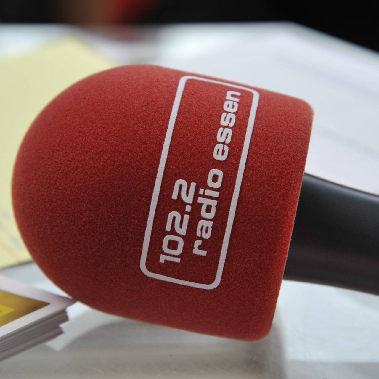 Das Mikro an schwarzem Stil mit rotem Schaumstoff-Ploppschutz mit dem Logo von Radio Essen drauf.
