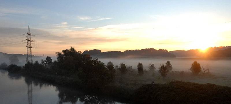Die Ruhr bei Essen Überruhr fließt entlang an einem bewaldeten Ufer im Sonnenaufgang.