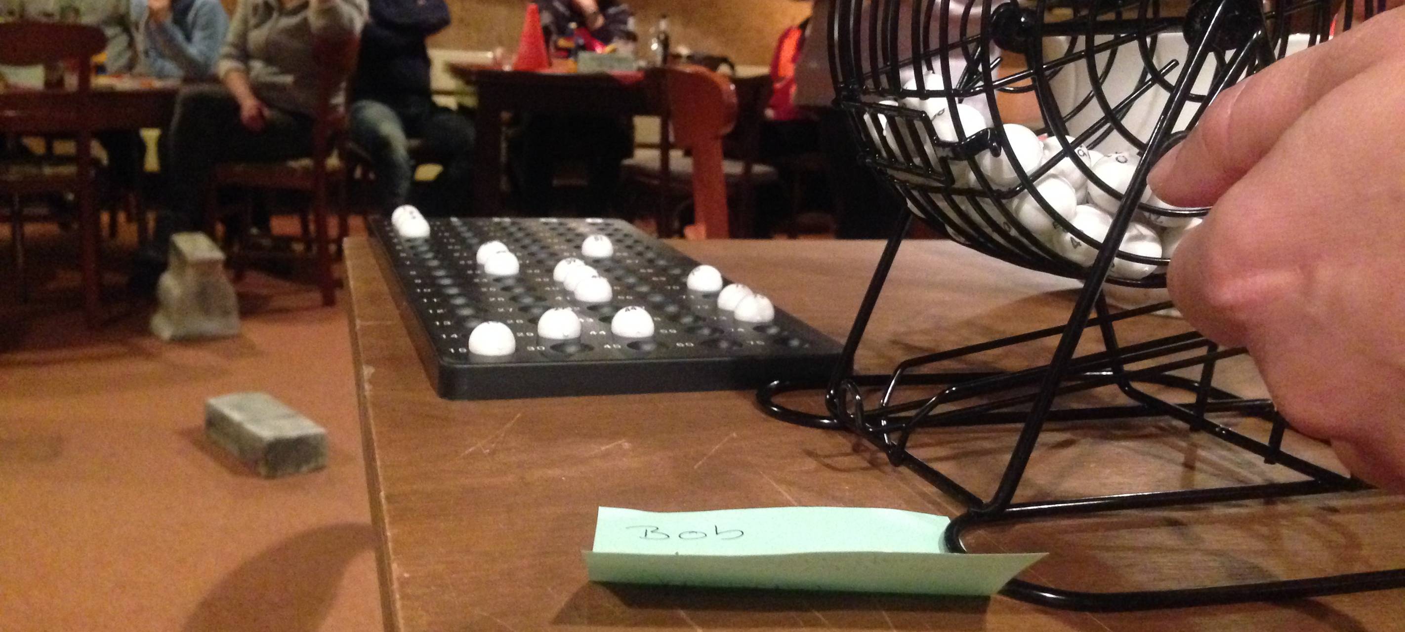 Bingo-Trommel und Bingo-Kugeln stehen in der Studiobühne in Leithe auf einem Tisch, dahinter sitzen Spieler.