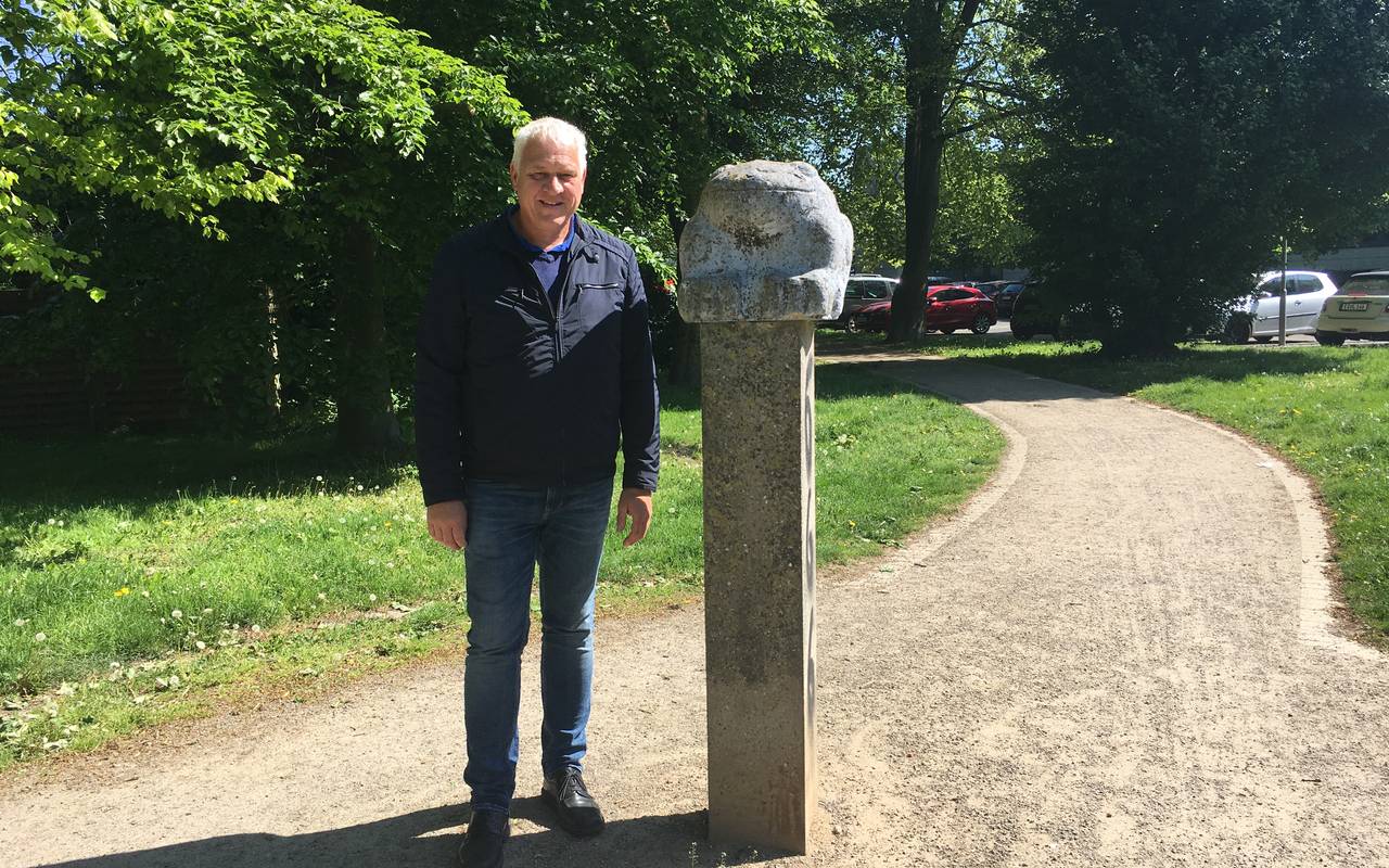 Ein älterer Mann, Landschaftsarchitekt Ulrich Falke, steht neben einem Steinfrosch auf einem Sockel in Schönebeck.