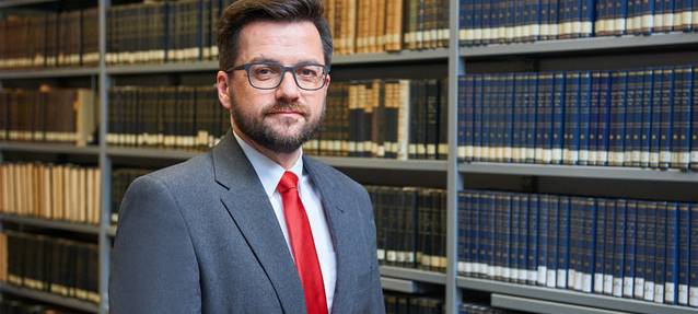 Chef der Essener SPD und Landtagsabgeordneter Thomas Kutschaty im Anzug vor einer Bücherwand