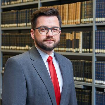 Chef der Essener SPD und Landtagsabgeordneter Thomas Kutschaty im Anzug vor einer Bücherwand