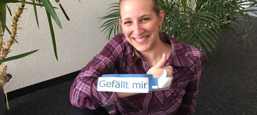 Radio Essen-Moderatorin Larissa Schmitz mit einem Gefällt-mir-Daumen von Facebook vor Blumen.