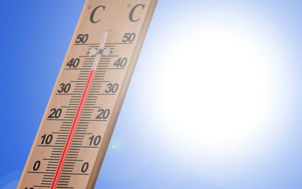 Holzthermometer zeigt 40 Grad mit knalliger Sonne dahinter