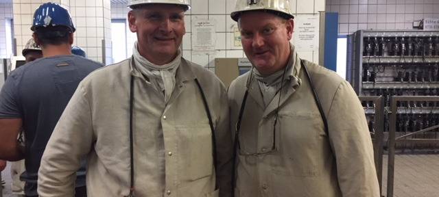 Zwei Teilnehmer der Grubenfahrt im Bergmanns-Outfit mit beigen Overall und Helm