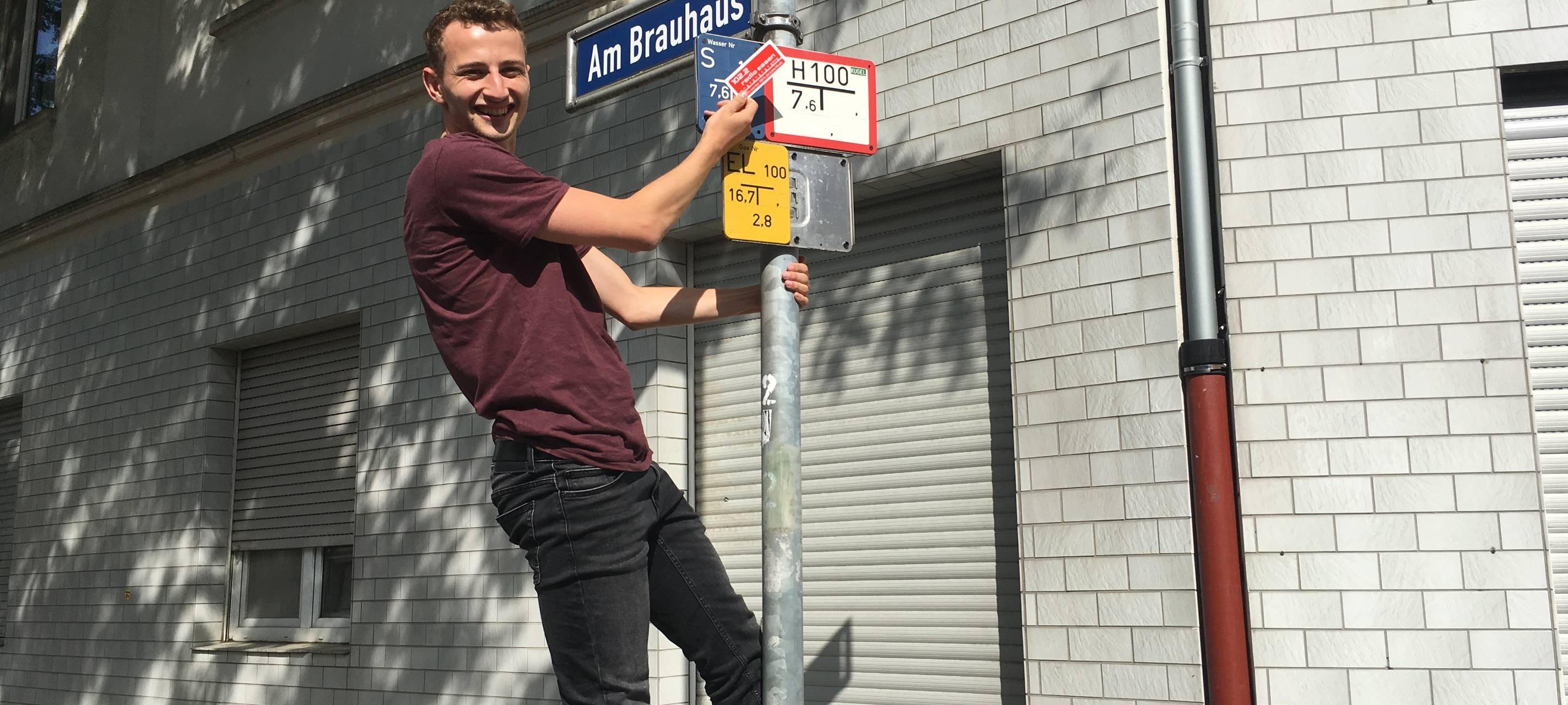 Joshua Windelschmidt von Radio Essen an einem Straßenschild