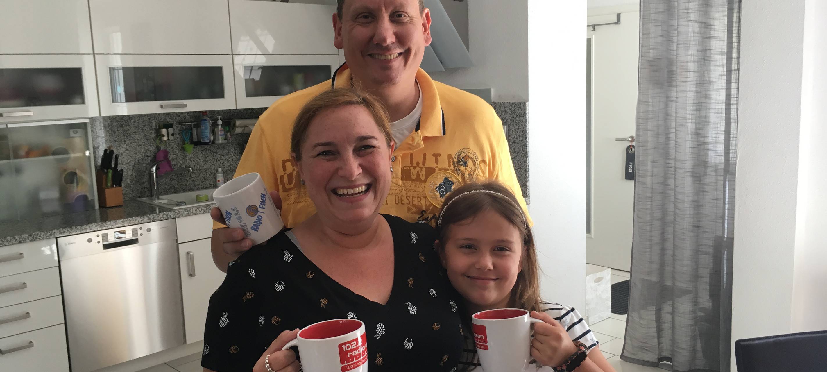 Frau, Mann und Kind mit Radio Essen-Tassen.