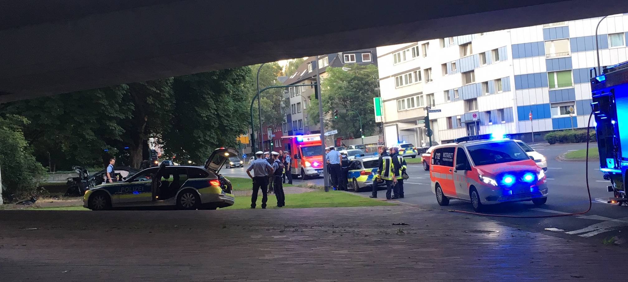 Im Hintergrund steht der Unfallwagen. Die Front ist komplett eingedrückt.