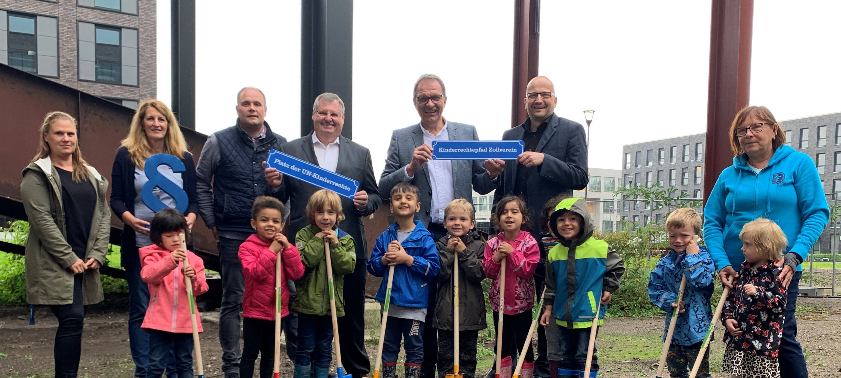 Erwachsene und Kinder legen die Grundsteine für den UN Kinderrechtepfad. Die Steine sind bunt bemalt, unter anderem mit den handabdrücken der Kinder.