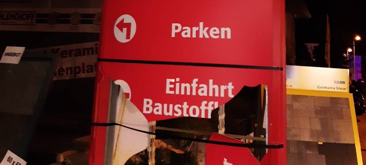 Das Bild zeigt die Werbetafel eines Baustoffhandels. Es hat ein großes Loch in der Mitte.