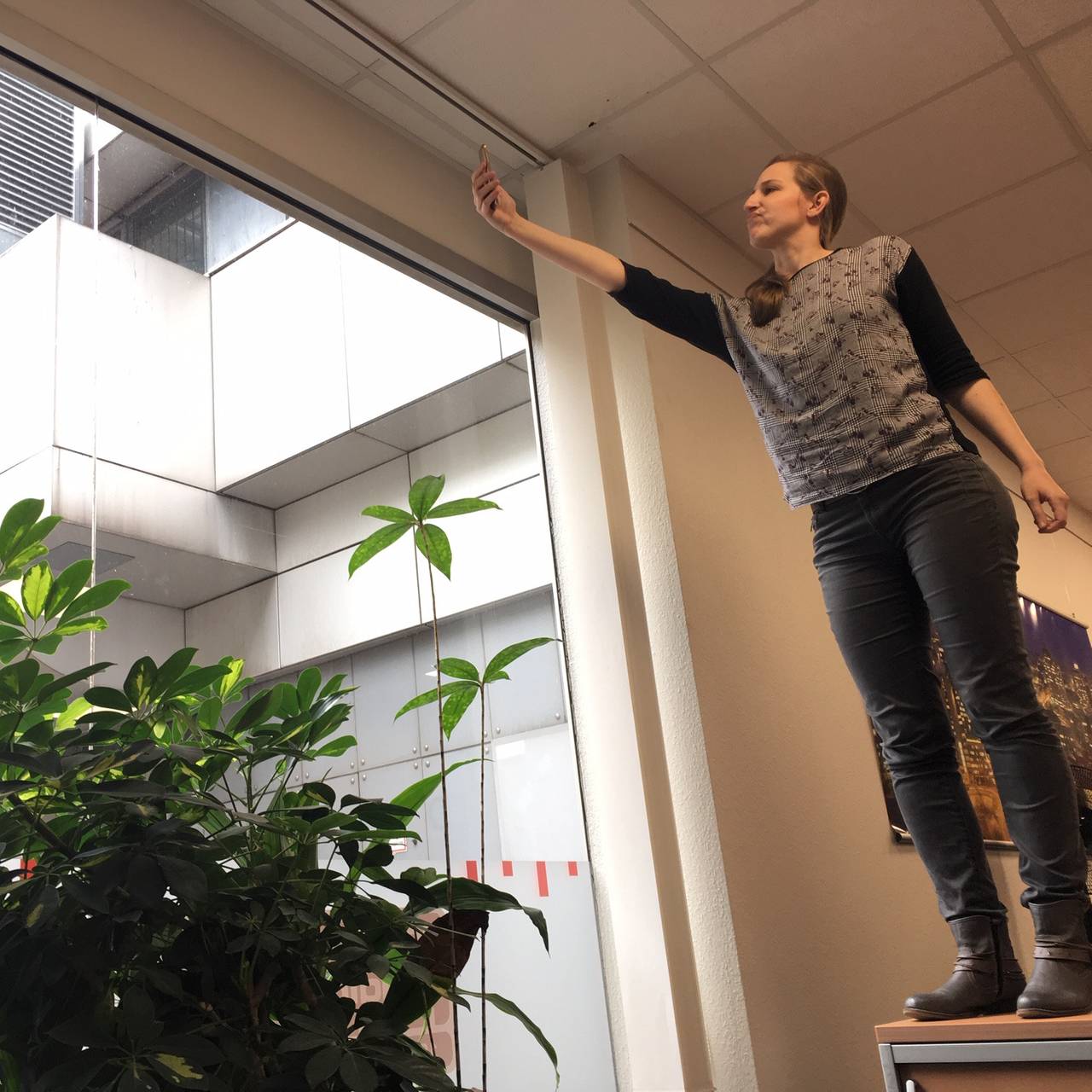 Larissa Schmitz von Radio Essen sucht mit ihrem Handy auf dem Schreibtisch am Fenster nach gutem Empfang.