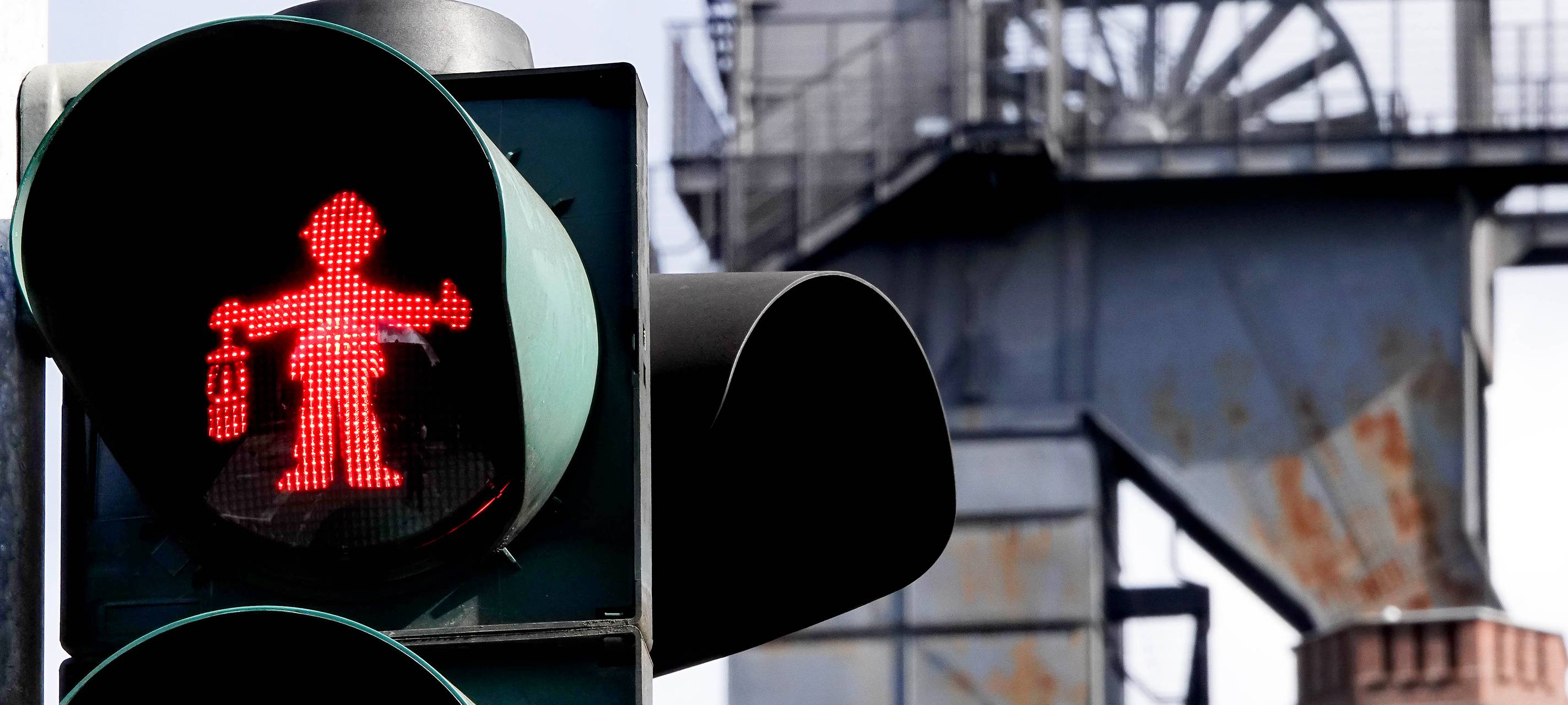 im Vordergrund ist eine Ampel mit Bergmann-Ampelmännchen. Sie steht in Bottrop, in der Nähe des Malakoffturms.